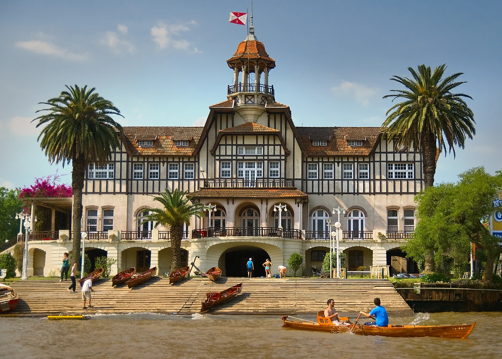Edificio histórico de un club de remo en Tigre con kayaks en el río.